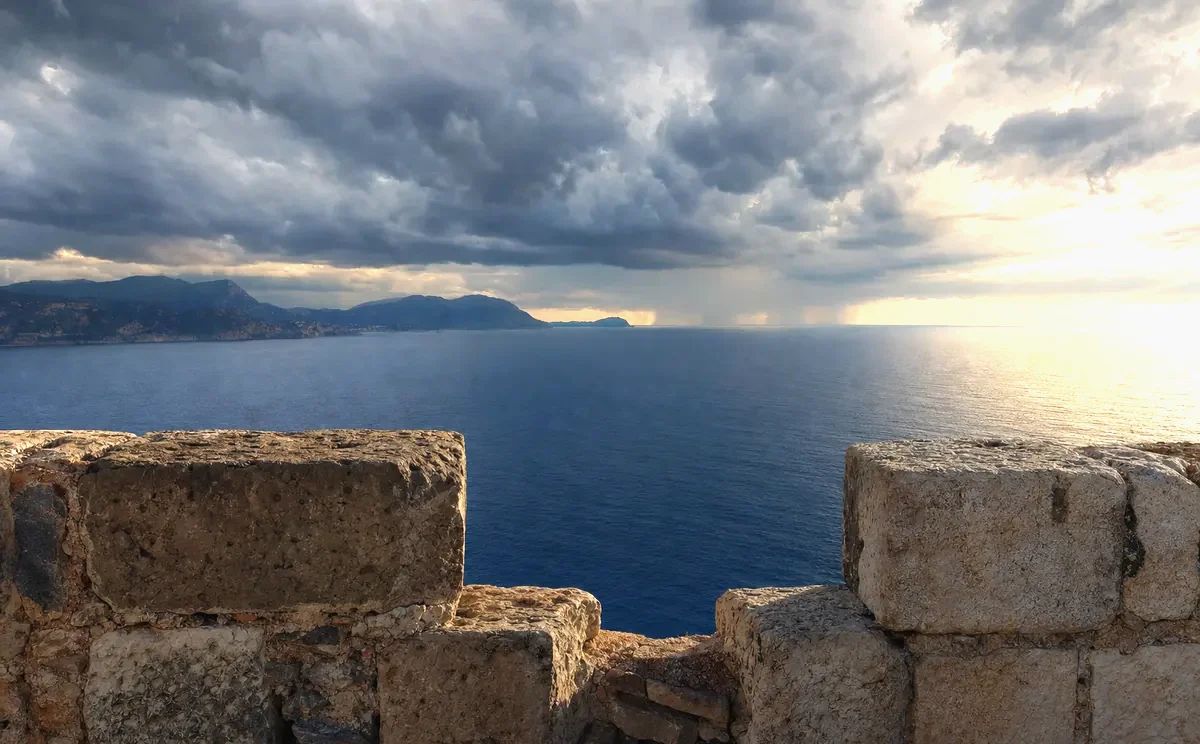 Ancient stone ramparts above the sea under a breaking sky